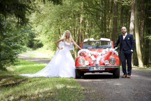 Brautpaar mit geschmückten VW Käfer im Wald