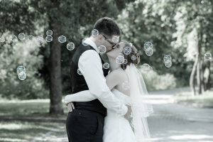 Hochzeitspaar küsst sich, umgeben von Seifenblasen