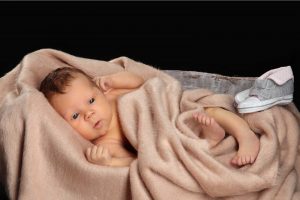 Neugeborenes, in eine Decke gehüllt, mit trapierten Babyschuhen