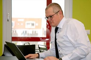 Businessfototgrafie eines Mannes im Anzug, auf den Laptop schauend