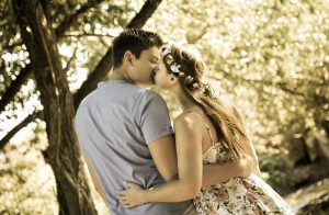 Portraitfoto eines sich küssenden Paares welches im Wald steht und von hinten fotografiert wurde