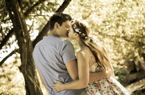 Portraitfoto eines sich küssenden Paares welches im Wald steht und von hinten fotografiert wurde