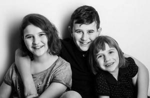 Portraitfoto von 3 Kindern die sich im Arm halten, Schwarzweißfotografie